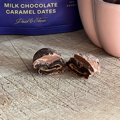 Dave & Jon's Drips milk chocolate caramel date cut in half showing the soft date centre and chocolate shell, with the 100 g pack behind